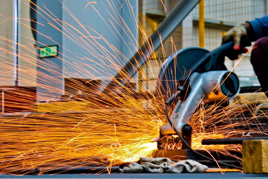 pexels photo 1145434 A worker operates a grinder cutting metal, creating a vibrant display of sparks in an industrial setting.