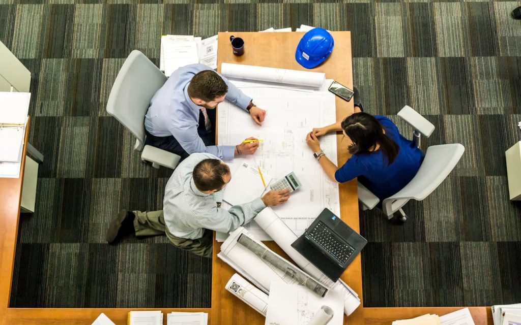pexels photo 416405 Top view of a team working on construction plans in an office setting.